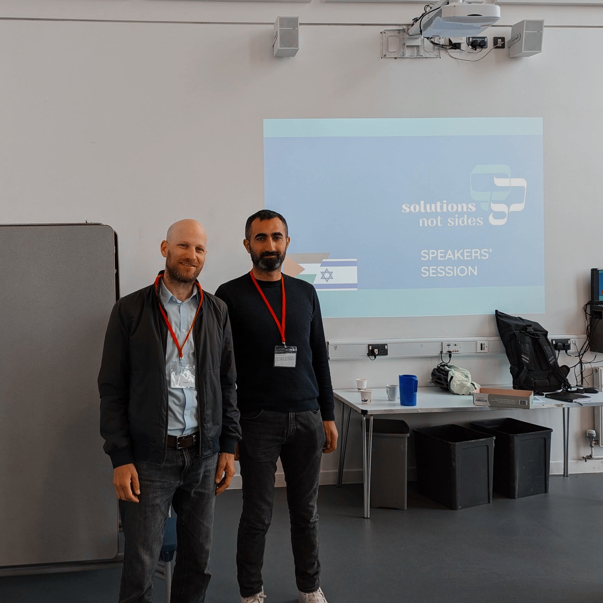 Magen, from Israel, and Hamze, from Palestine, standing together at the front of a classroom before a workshop  this week at a school in North London